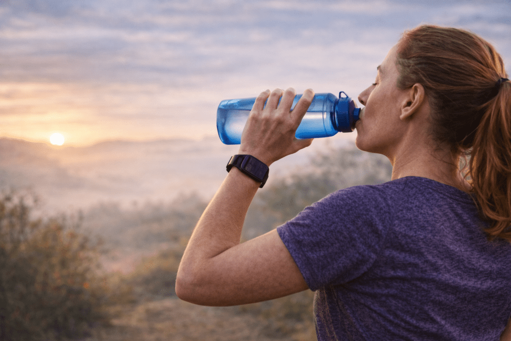 Femme de 40 ans courant en endurance fondamentale et s’hydratant pendant une sortie à allure confortable.