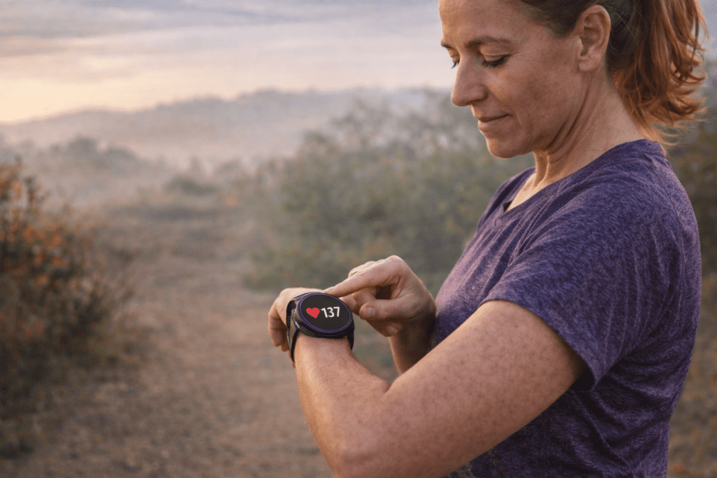 Femme de 40 ans courant en endurance fondamentale en zone 2, avec une respiration calme et un effort contrôlé qui vérifie sa montre cardio.